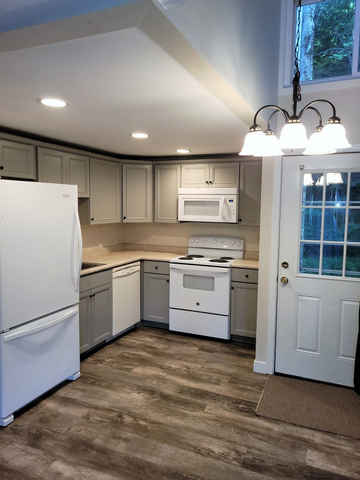 Inspiration for a small country l-shaped eat-in kitchen in Boston with a drop-in sink, recessed-panel cabinets, grey cabinets, laminate benchtops, white appliances, vinyl floors, no island, brown floor and beige benchtop.