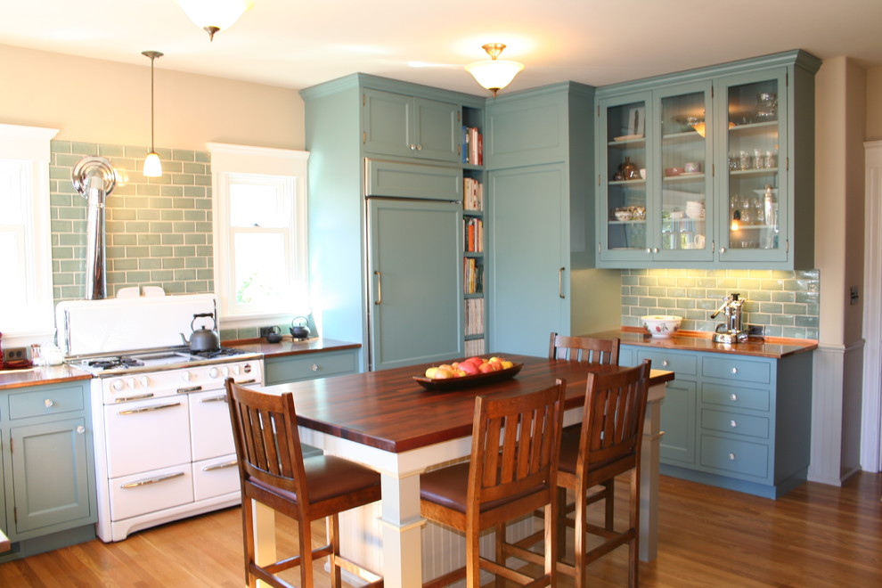 Mid-sized traditional u-shaped eat-in kitchen in San Francisco with glass-front cabinets, copper benchtops, blue cabinets, blue splashback, subway tile splashback, white appliances, a single-bowl sink, medium hardwood floors and with island.