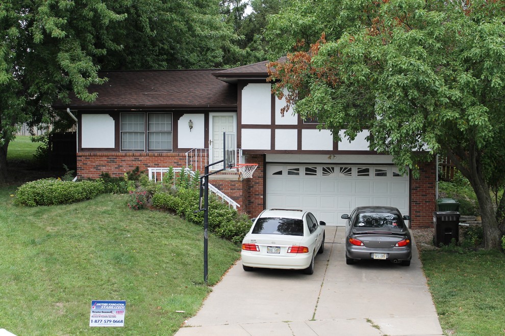This is an example of a mid-sized traditional split-level white exterior in Omaha with mixed siding and a hip roof.