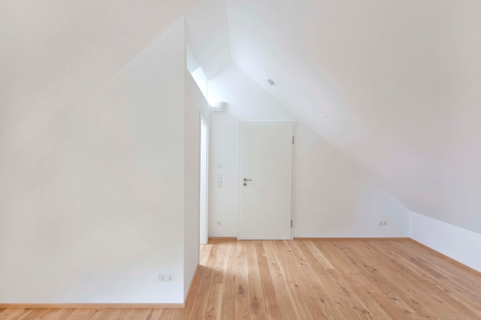 Aménagement d'un salon contemporain ouvert avec un mur blanc et un sol en bois brun.