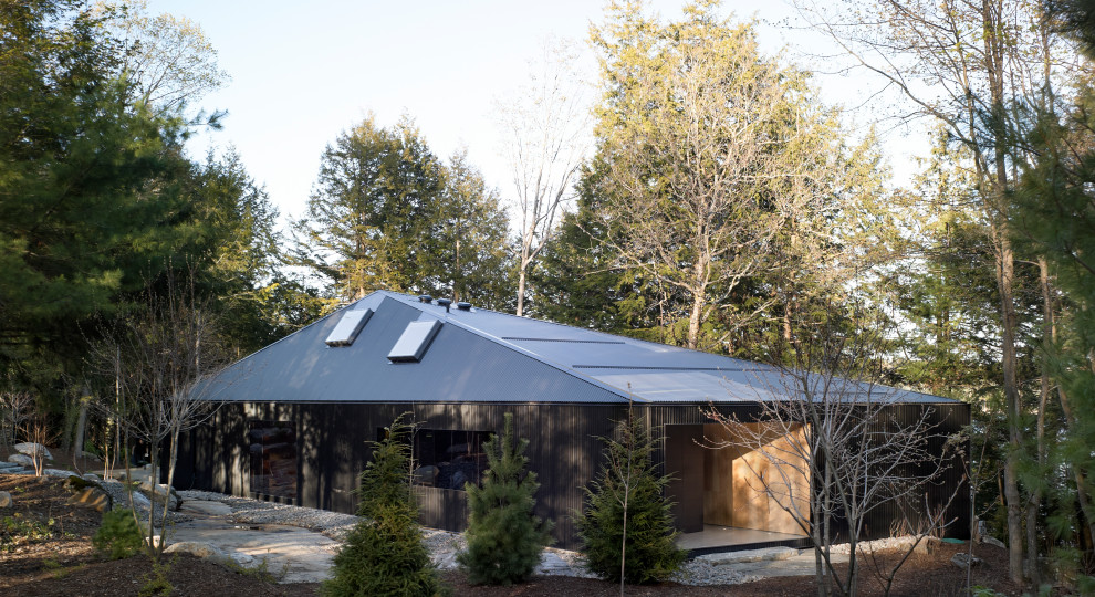 Idées déco pour une grande façade de maison noire contemporaine en planches et couvre-joints de plain-pied avec un toit à quatre pans, un toit en métal et un toit noir.