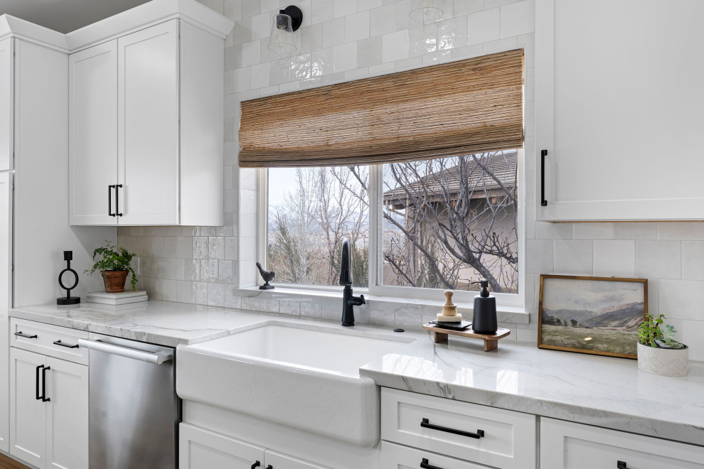 Inspiration for a transitional vinyl floor and brown floor kitchen remodel with a farmhouse sink, shaker cabinets, white cabinets, quartzite countertops, white backsplash and stainless steel appliances