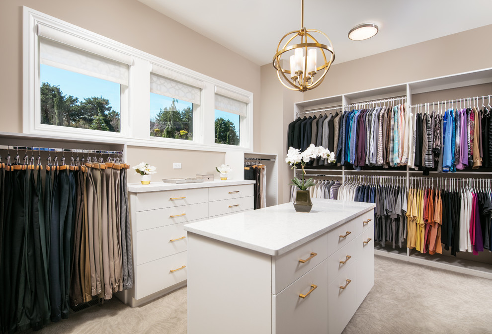 Photo of a large transitional gender-neutral dressing room in Omaha with flat-panel cabinets, white cabinets, carpet and beige floor.