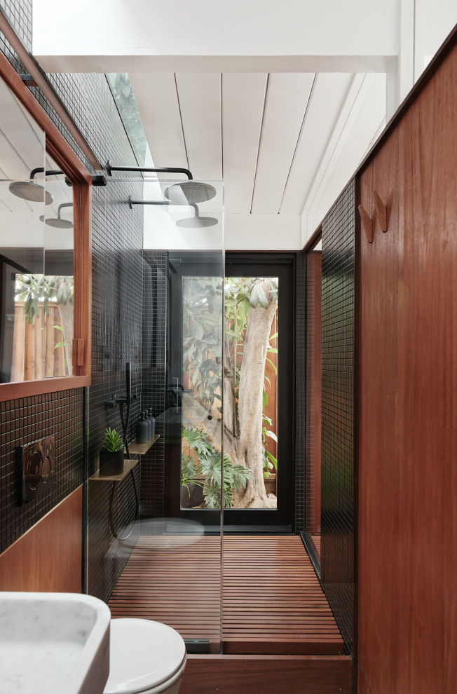 Photo of a midcentury bathroom in San Francisco with a double shower, black tile, mosaic tile, medium hardwood floors, brown floor, an open shower, vaulted and wood walls.