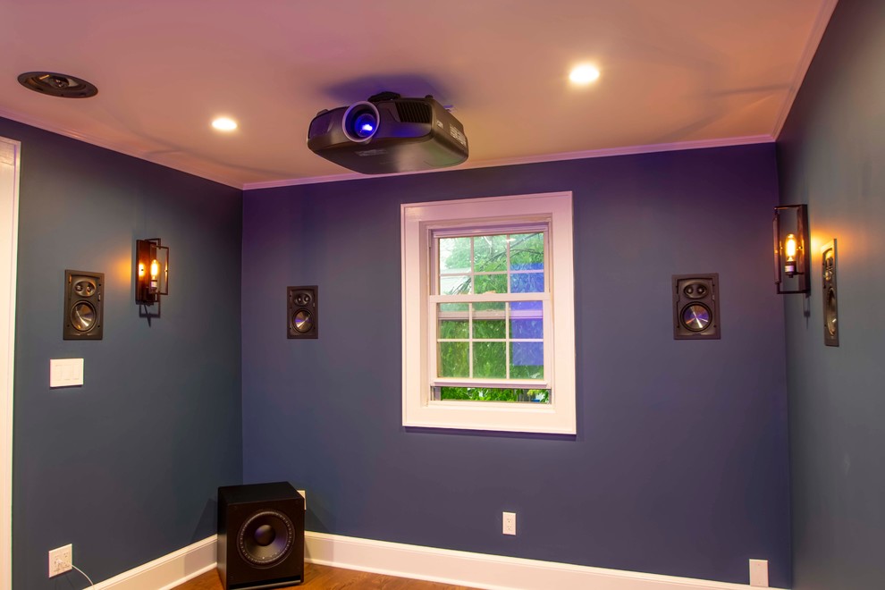 Photo of a small contemporary enclosed home theatre in New York with blue walls, medium hardwood floors, a projector screen and brown floor.
