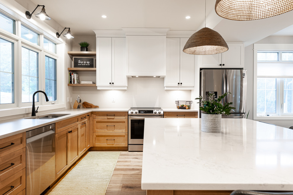 Inspiration for a mid-sized transitional l-shaped laminate floor and brown floor eat-in kitchen remodel in Toronto with an undermount sink, recessed-panel cabinets, white cabinets, quartz countertops, stainless steel appliances, an island and white countertops
