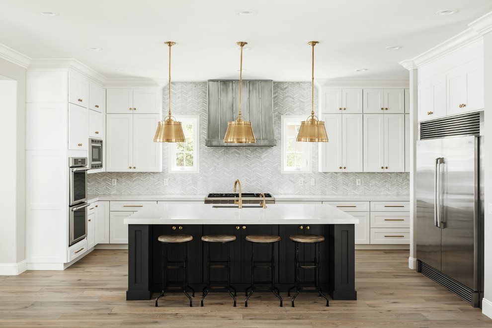 Design ideas for a large transitional u-shaped open plan kitchen in Phoenix with an undermount sink, shaker cabinets, quartz benchtops, grey splashback, marble splashback, stainless steel appliances, light hardwood floors, with island, beige floor and white benchtop.