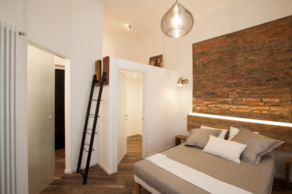 Design ideas for a mid-sized industrial master bedroom in Milan with white walls, porcelain floors and brown floor.