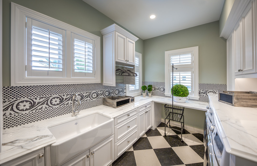 Design ideas for a mid-sized mediterranean u-shaped dedicated laundry room in Other with a farmhouse sink, recessed-panel cabinets, white cabinets, granite benchtops, green walls, ceramic floors, a side-by-side washer and dryer and multi-coloured floor.