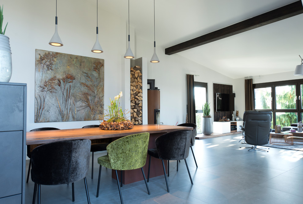 Inspiration for a large contemporary dining room in Nuremberg with white walls, concrete floors, a wood stove, a metal fireplace surround and grey floor.
