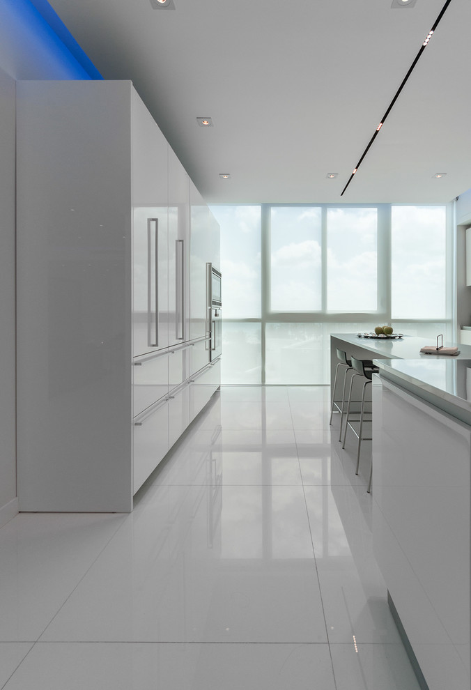 This is an example of a modern u-shaped eat-in kitchen in Miami with flat-panel cabinets and white cabinets.