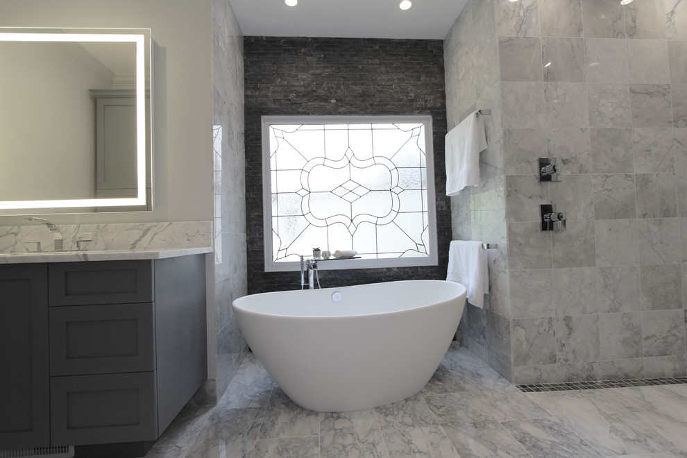 Inspiration for a large contemporary master bathroom in Atlanta with shaker cabinets, grey cabinets, a freestanding tub, a curbless shower, a two-piece toilet, black and white tile, gray tile, white tile, stone tile, grey walls, marble floors, an undermount sink and marble benchtops.