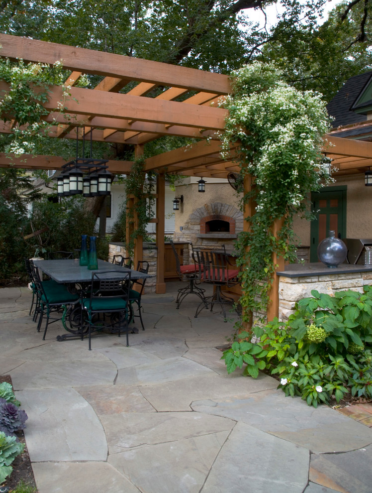 Mid-sized arts and crafts backyard patio in Chicago with an outdoor kitchen, natural stone pavers and a pergola.
