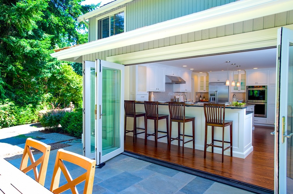 Large transitional u-shaped dark wood floor eat-in kitchen photo in Seattle with an undermount sink, shaker cabinets, white cabinets, quartz countertops, beige backsplash, glass tile backsplash, stainless steel appliances and an island