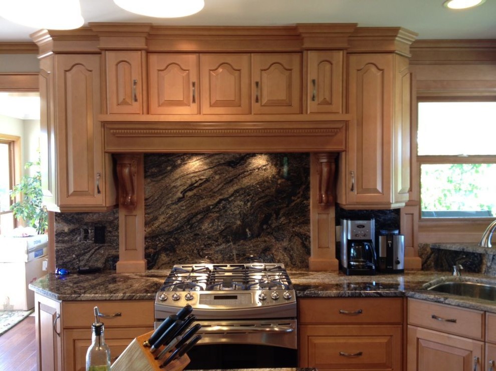Example of a mid-sized transitional l-shaped medium tone wood floor kitchen pantry design in Toronto with granite countertops, stone slab backsplash, a double-bowl sink, raised-panel cabinets, medium tone wood cabinets, multicolored backsplash, stainless steel appliances and an island