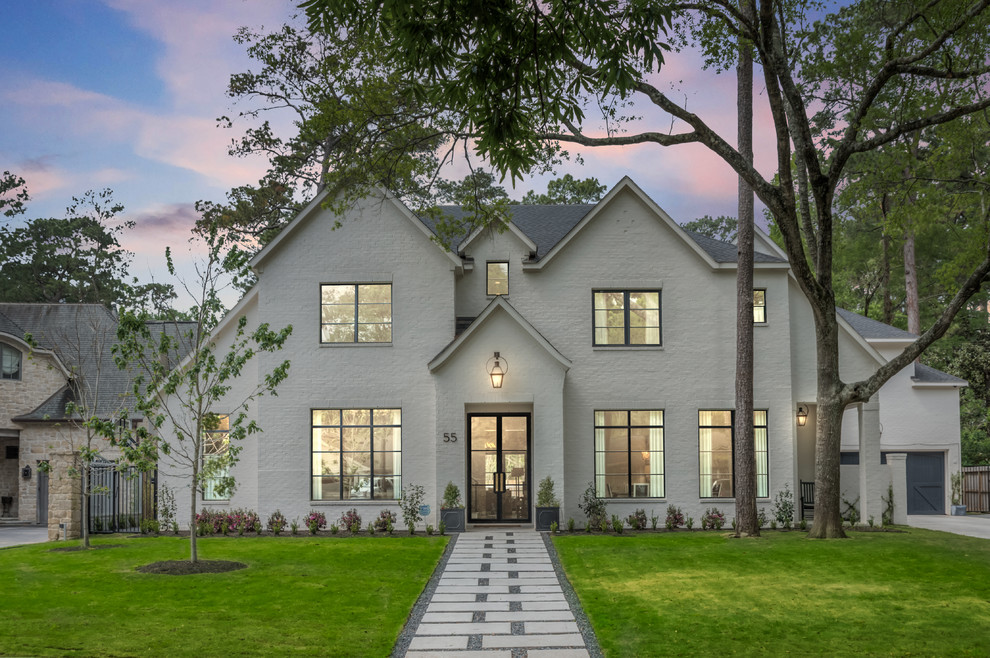 Photo of an expansive transitional two-storey brick white house exterior in Houston with a gable roof and a shingle roof.