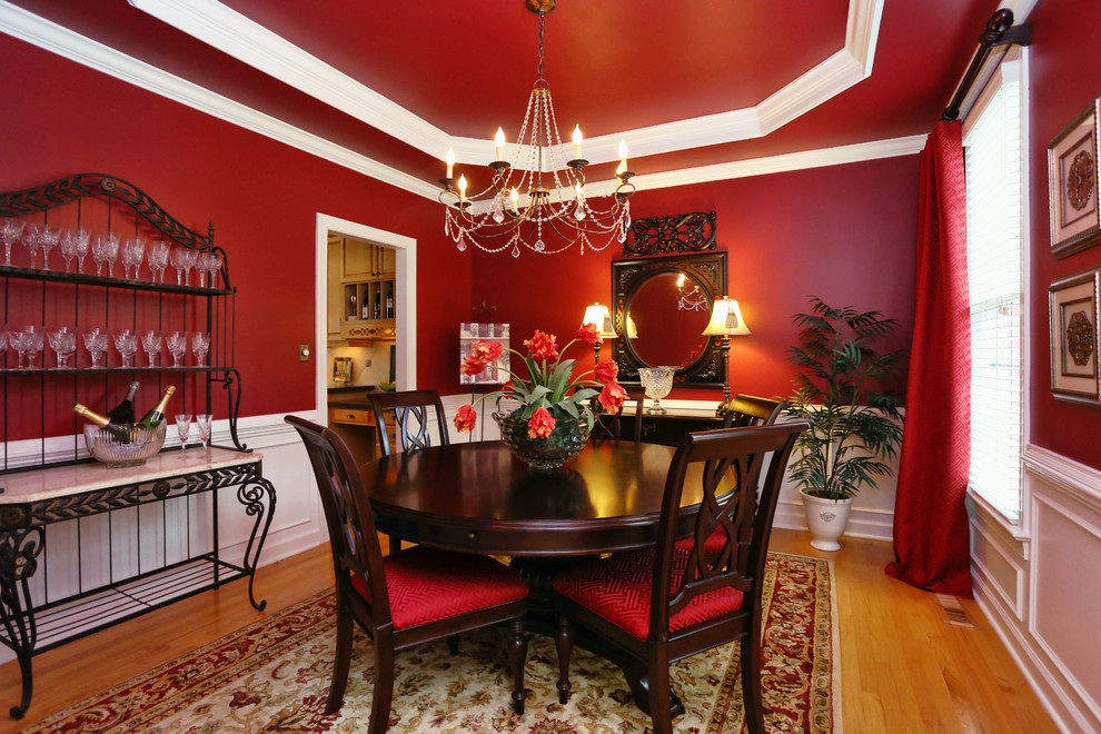 Enclosed dining room - mid-sized transitional medium tone wood floor, brown floor and tray ceiling enclosed dining room idea in Raleigh with red walls and no fireplace
