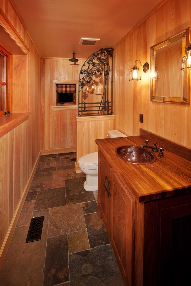 This is an example of a country kids bathroom in Other with a drop-in sink, recessed-panel cabinets, medium wood cabinets, wood benchtops, an open shower, a two-piece toilet, beige walls and slate floors.