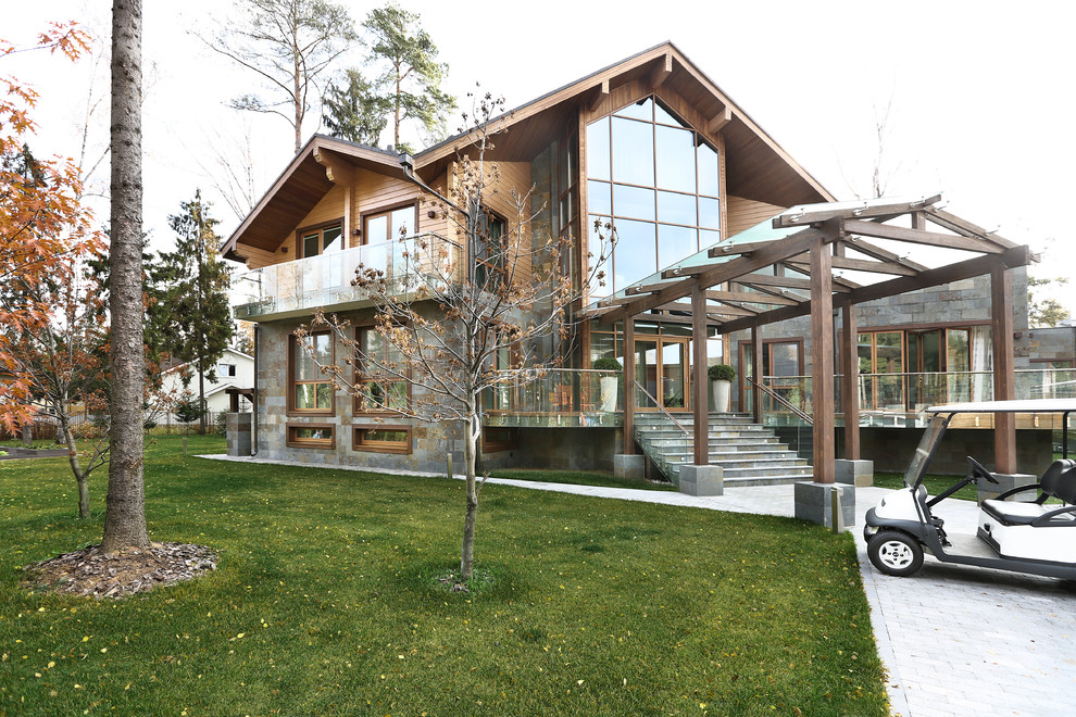 Inspiration for a large contemporary two-storey brown exterior in Moscow with wood siding and a gable roof.