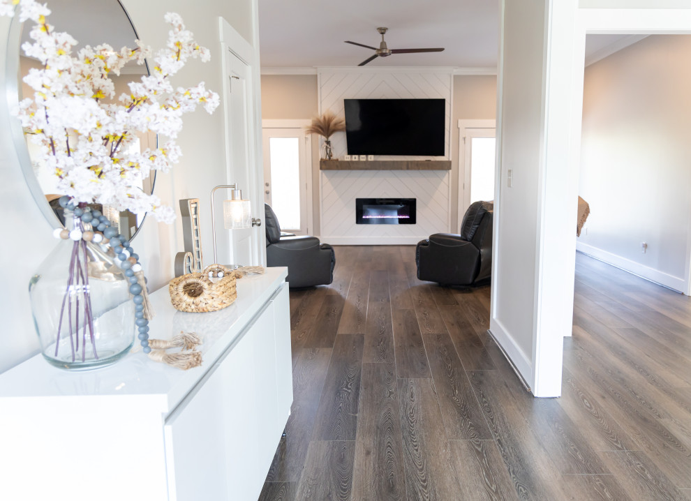 Small transitional formal open concept living room in Birmingham with white walls, vinyl floors, a standard fireplace, a concrete fireplace surround, a wall-mounted tv, brown floor and recessed.