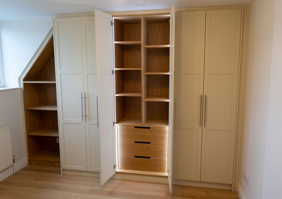 Design ideas for a large classic standard wardrobe in Gloucestershire with shaker cabinets, beige cabinets and light hardwood flooring.
