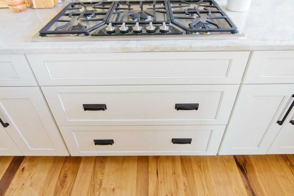 Eat-in kitchen - large transitional u-shaped light wood floor eat-in kitchen idea in Denver with a farmhouse sink, shaker cabinets, white cabinets, quartz countertops, multicolored backsplash, porcelain backsplash, stainless steel appliances and an island