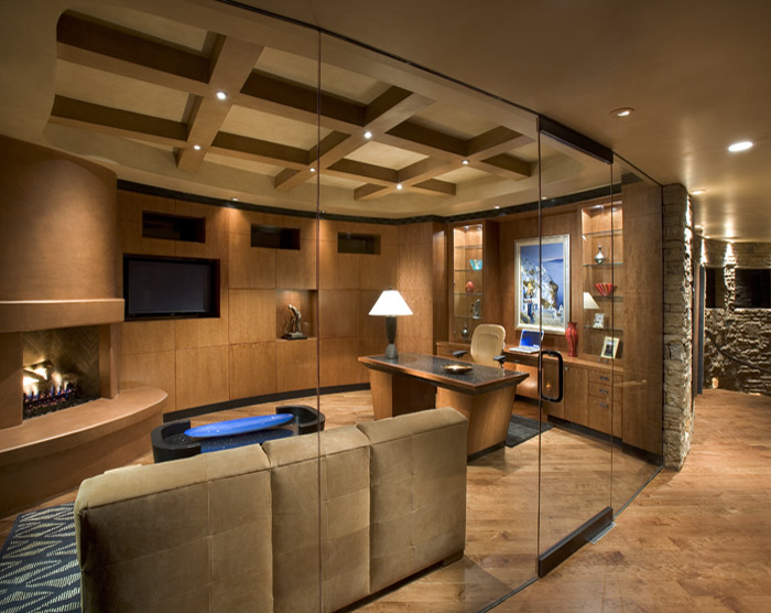Large contemporary study room in Phoenix with brown walls, dark hardwood floors, a corner fireplace, a plaster fireplace surround and a freestanding desk.