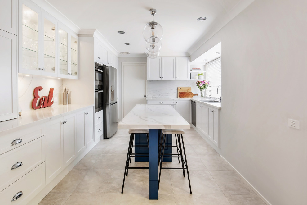 Photo of a mid-sized transitional galley open plan kitchen in Sydney with a drop-in sink, shaker cabinets, white cabinets, quartz benchtops, white splashback, engineered quartz splashback, stainless steel appliances, porcelain floors, with island, beige floor and white benchtop.