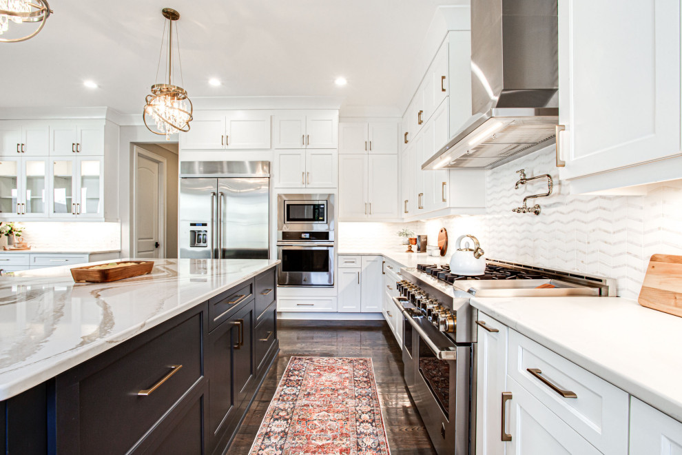 Example of a large transitional u-shaped medium tone wood floor and brown floor open concept kitchen design in Atlanta with an undermount sink, shaker cabinets, white cabinets, quartz countertops, white backsplash, subway tile backsplash, stainless steel appliances, an island and white countertops