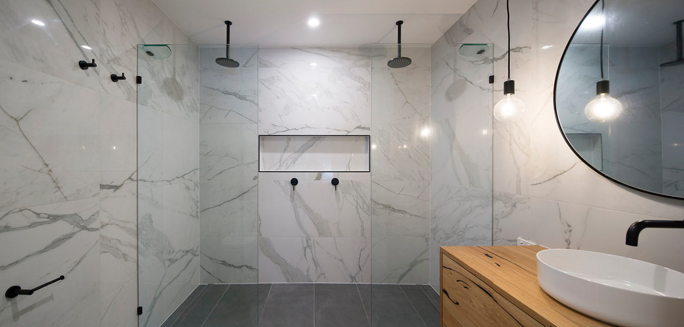 Photo of a mid-sized traditional master wet room bathroom in Brisbane with flat-panel cabinets, light wood cabinets, a one-piece toilet, white tile, marble, porcelain floors, a vessel sink, wood benchtops, grey floor and an open shower.