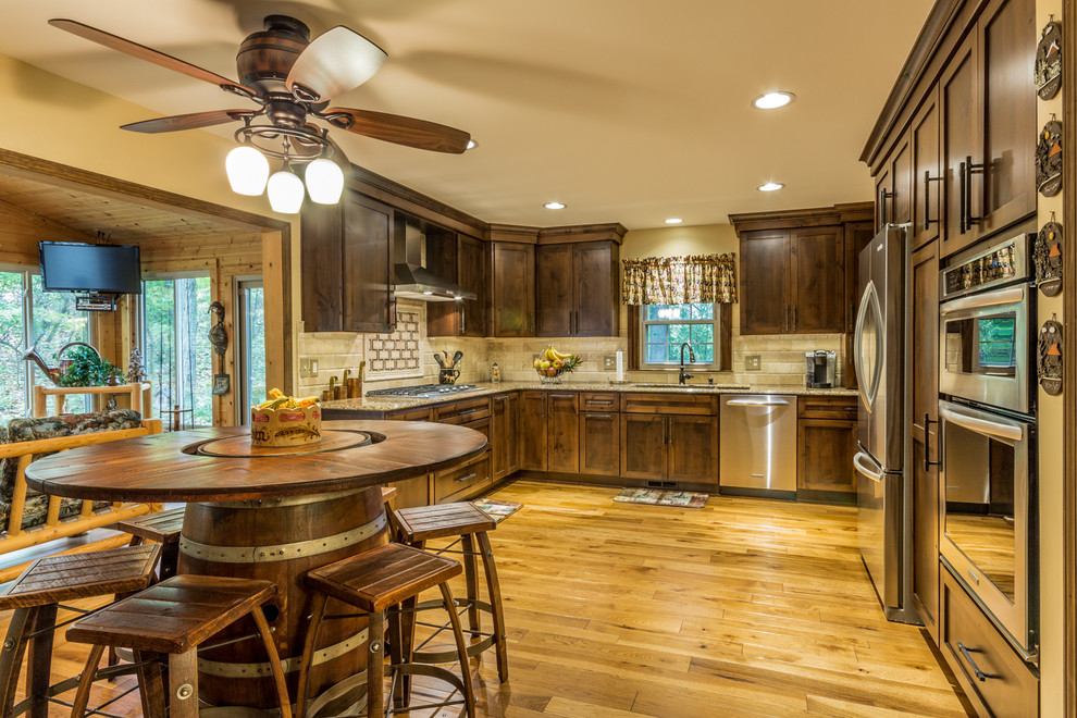 Example of a mid-sized mountain style u-shaped medium tone wood floor eat-in kitchen design in Detroit with an undermount sink, shaker cabinets, dark wood cabinets, quartz countertops, beige backsplash, subway tile backsplash, stainless steel appliances and no island