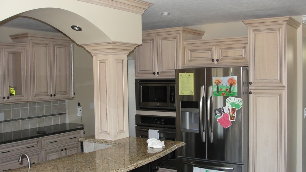 Mid-sized l-shaped medium tone wood floor open concept kitchen photo with light wood cabinets, granite countertops, beige backsplash, ceramic backsplash, stainless steel appliances and an island