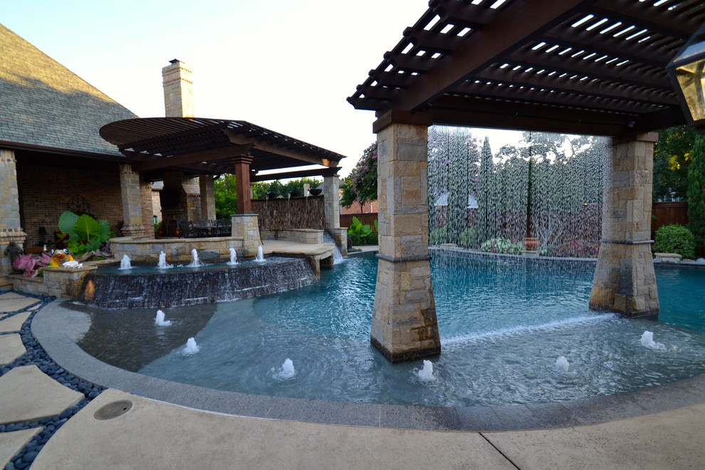 Large transitional backyard custom-shaped pool in Dallas with stamped concrete and a water feature.