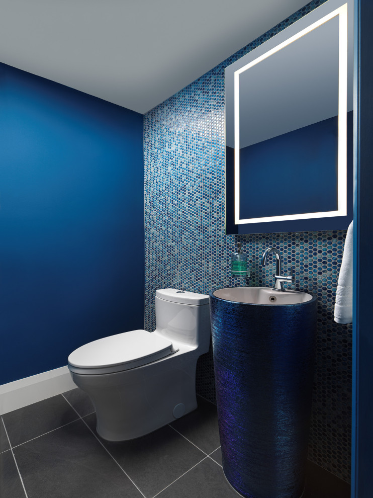 Design ideas for a mid-sized contemporary powder room in Toronto with blue cabinets, a one-piece toilet, blue tile, ceramic tile, blue walls, porcelain floors, a pedestal sink, grey floor and a freestanding vanity.