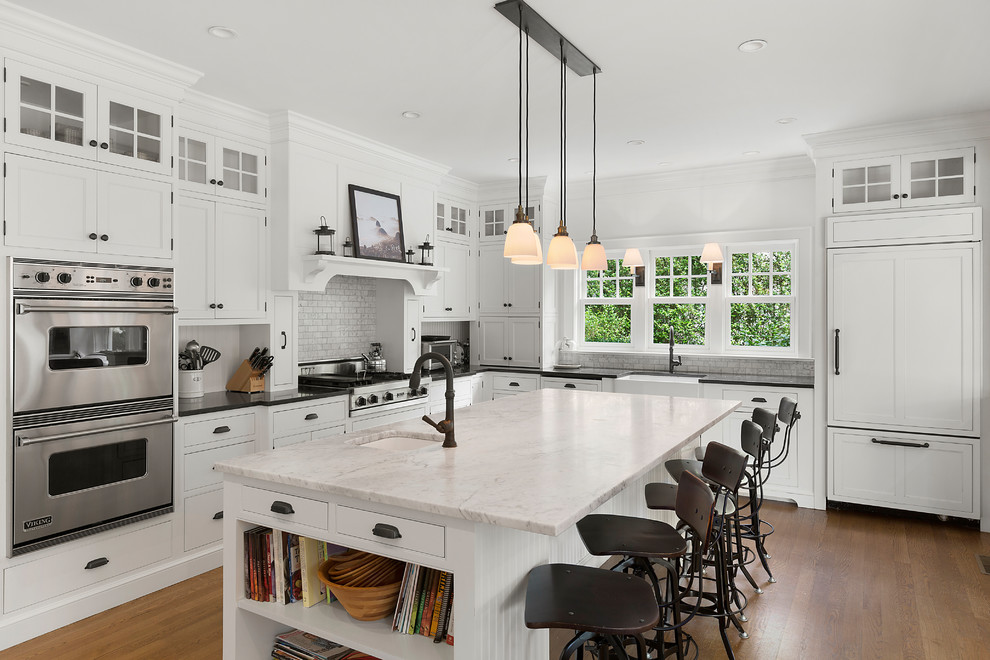 This is an example of a beach style l-shaped kitchen in Philadelphia with an undermount sink, shaker cabinets, white cabinets, white splashback, panelled appliances, medium hardwood floors and with island.