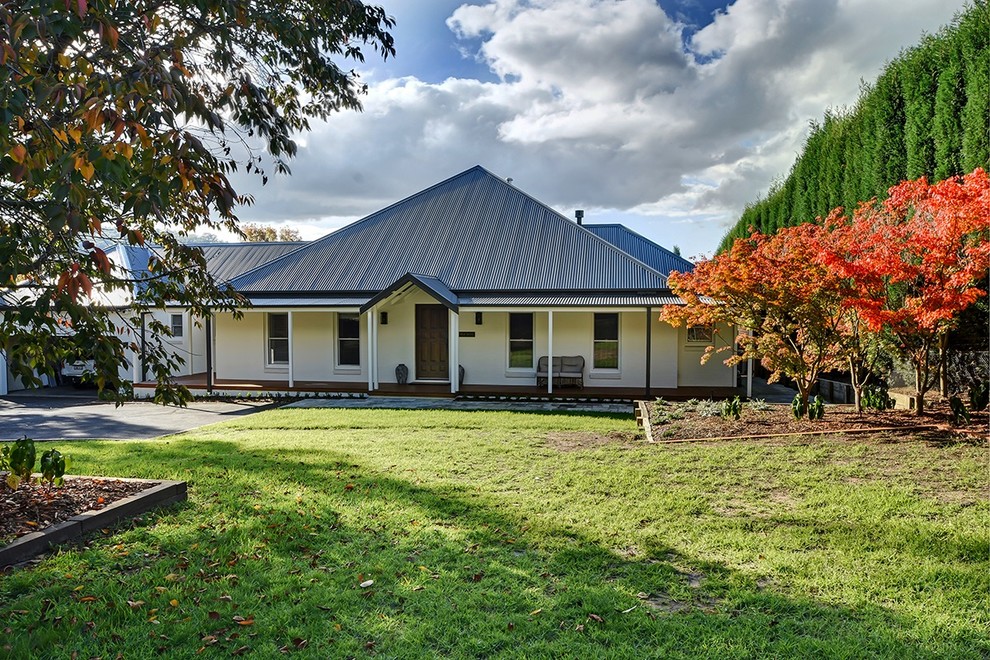 This is an example of a large transitional two-storey white house exterior in Other with a gable roof and a metal roof.