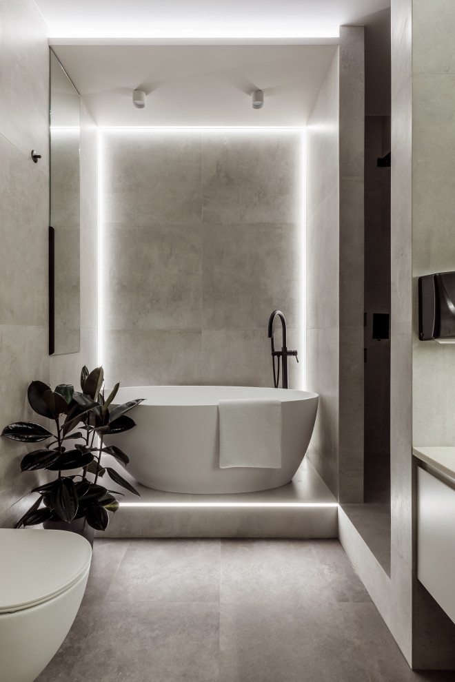 Inspiration för mellanstora moderna en-suite badrum, med släta luckor, beige skåp, ett fristående badkar, en dusch i en alkov, en vägghängd toalettstol, grå kakel, porslinskakel, vinylgolv, granitbänkskiva, grått golv och med dusch som är öppen