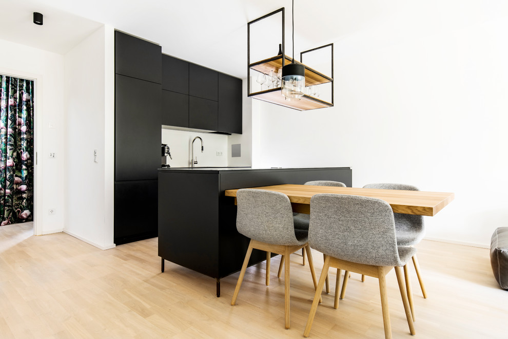 Photo of a mid-sized contemporary galley open plan kitchen in Munich with flat-panel cabinets, black cabinets, light hardwood floors, with island and beige floor.