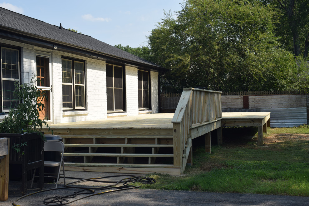 Example of a large backyard ground level wood railing deck design with a roof extension
