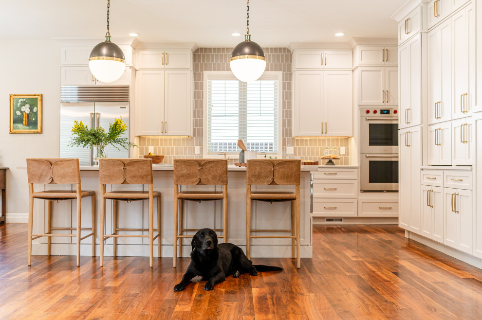 Large transitional l-shaped dark wood floor and brown floor open concept kitchen photo in Denver with a farmhouse sink, shaker cabinets, beige cabinets, quartz countertops, beige backsplash, ceramic backsplash, stainless steel appliances, an island and white countertops