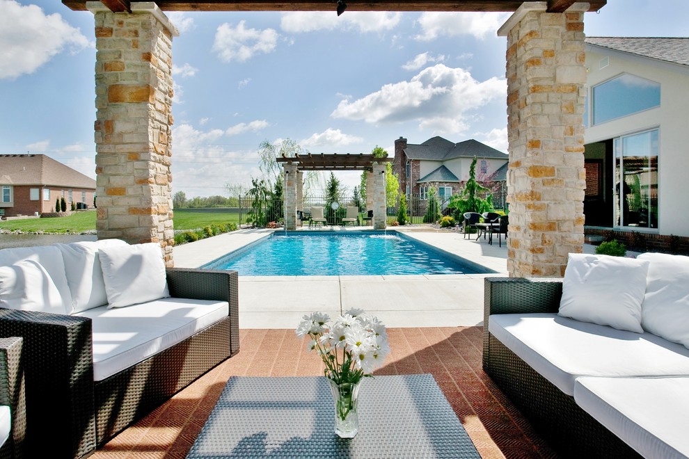 Photo of a mid-sized contemporary backyard rectangular lap pool in St Louis with a water feature and stamped concrete.