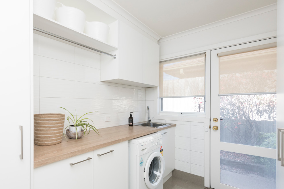 Mid-sized contemporary dedicated laundry room in Melbourne with white cabinets, laminate benchtops, white walls and porcelain floors.