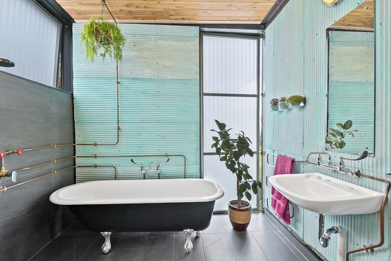 Design ideas for a mid-sized industrial master bathroom in Christchurch with a claw-foot tub, metal tile, green walls, ceramic floors, a drop-in sink and black floor.