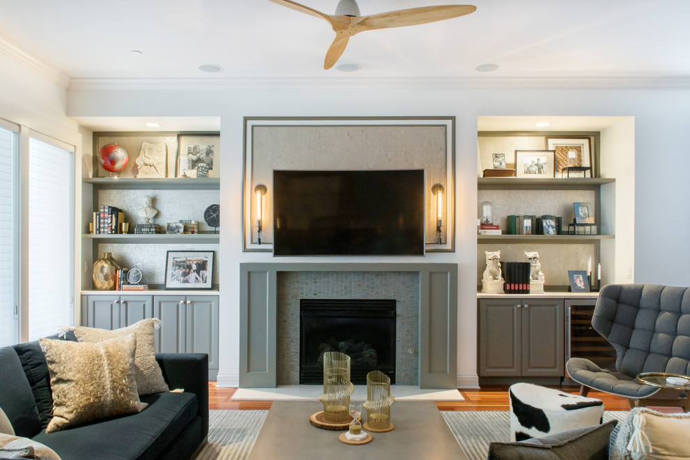 This is an example of a mid-sized transitional open concept living room in St Louis with grey walls, medium hardwood floors, a standard fireplace, a stone fireplace surround and a wall-mounted tv.