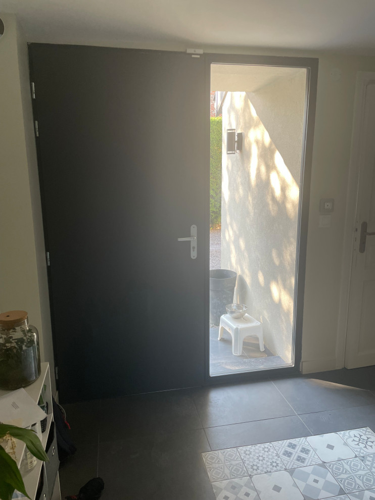 Diseño de distribuidor contemporáneo de tamaño medio con paredes beige, suelo de baldosas de cerámica, puerta simple, puerta negra y suelo gris