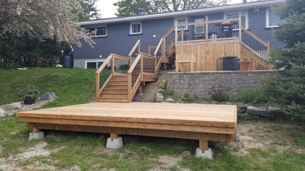Photo of a large modern backyard and ground level deck in Ottawa with with dock, no cover and mixed railing.