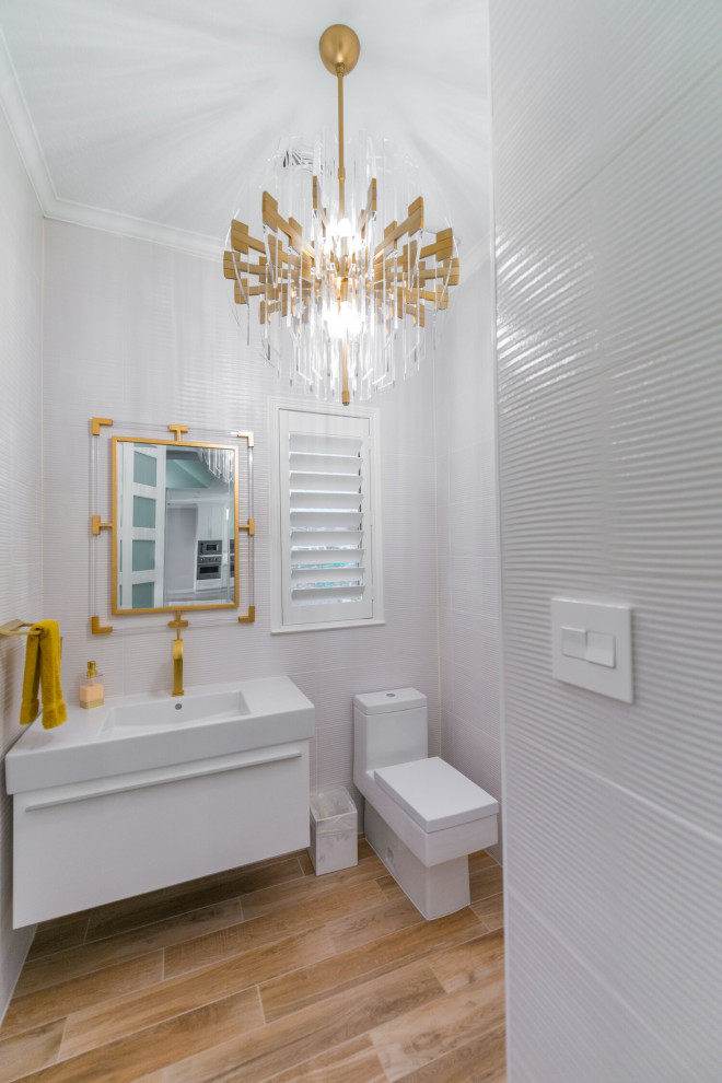 Modern inredning av ett mellanstort vit vitt toalett, med släta luckor, vita skåp, en toalettstol med hel cisternkåpa, grå kakel, porslinskakel, grå väggar, vinylgolv, ett integrerad handfat, bänkskiva i kvartsit och brunt golv