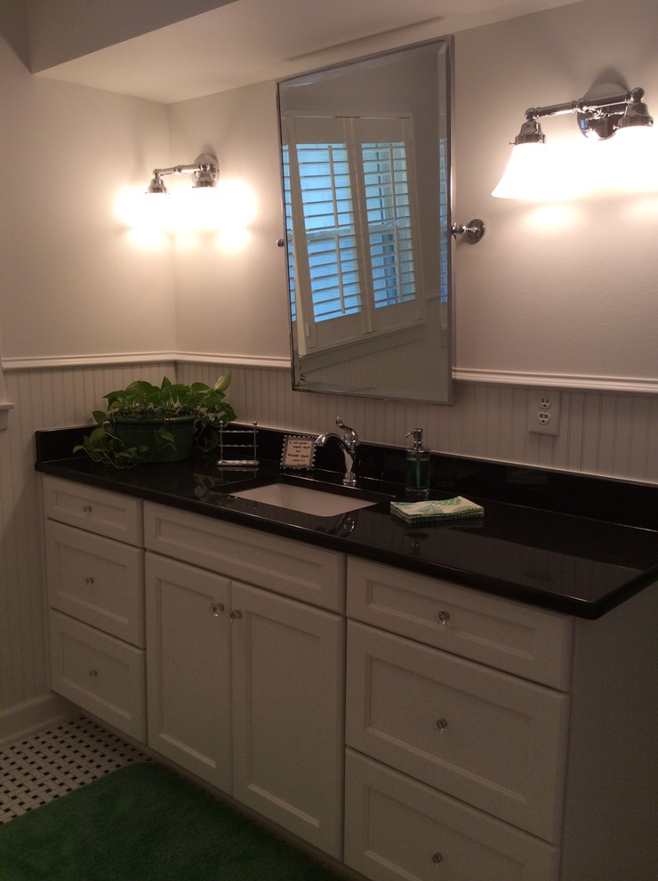 This is an example of a mid-sized transitional kids bathroom in Birmingham with an undermount sink, flat-panel cabinets, white cabinets, granite benchtops, a drop-in tub, a shower/bathtub combo, a two-piece toilet, black tile, ceramic tile, white walls and ceramic floors.