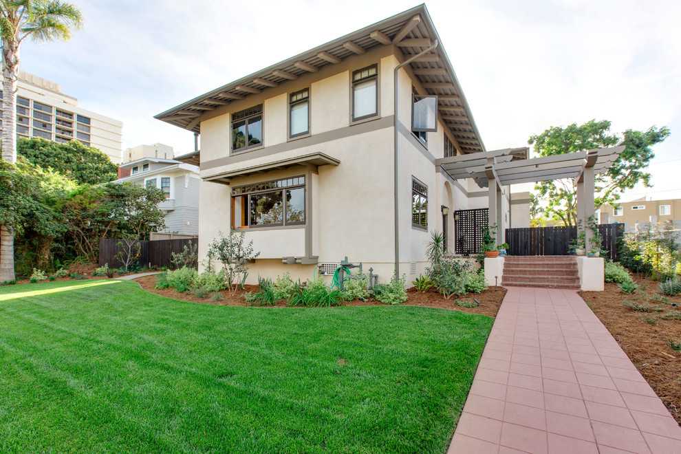 Inspiration for a large mediterranean beige two-story stucco house exterior remodel in San Diego with a hip roof and a shingle roof
