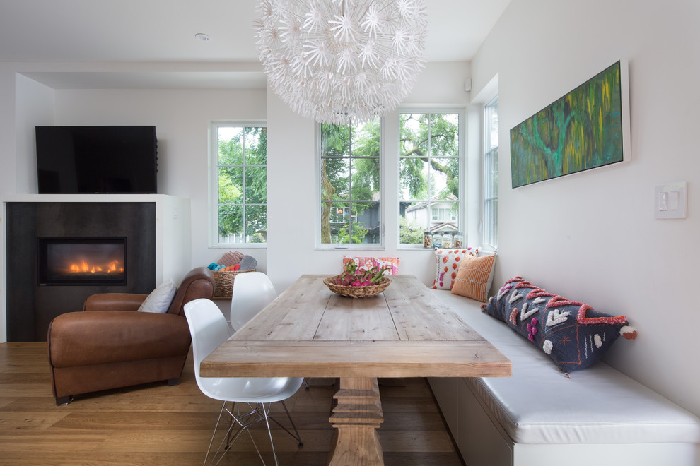This is an example of a small transitional open plan dining in Vancouver with white walls, a standard fireplace, a metal fireplace surround, light hardwood floors and beige floor.